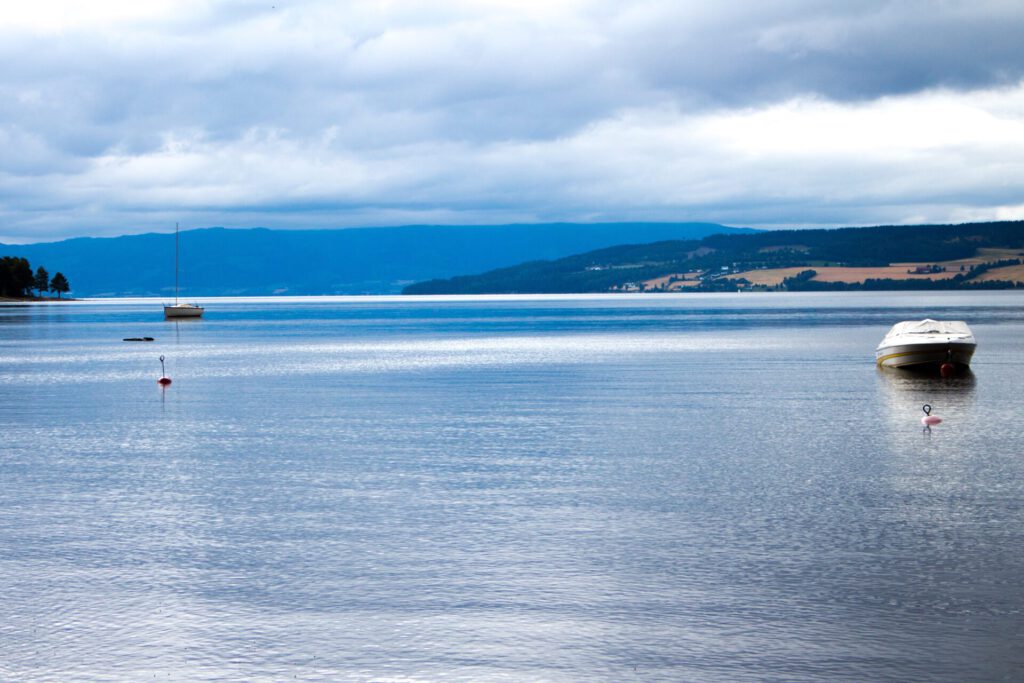 Vista de un lago tranquilo con embarcaciones ancladas y cielo nublado agua consciente 1