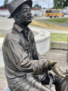 Escultura de bronce de un hombre sentado junto a una fuente con agua conservada