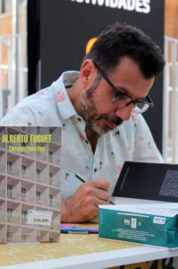 Hombre firmando un libro en mesa de presentación, imagen para promover agua responsable