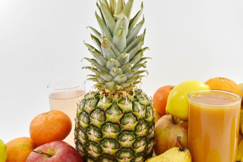 Surtido de alimentos saludables con piña, cítricos, manzana, pera y vasos de zumo