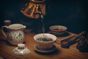 Tetera vertiendo té en una taza de porcelana sobre una bandeja de madera, evocando almacenamiento energia eficiencia energetica