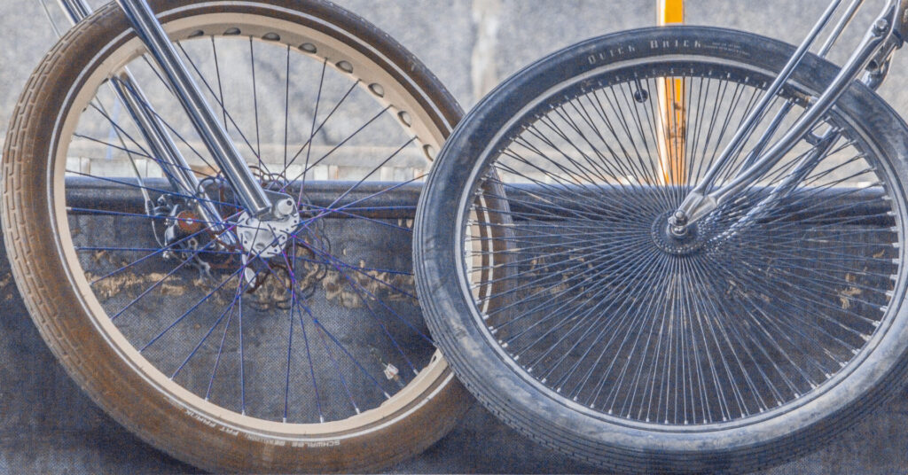 Primer plano de dos ruedas de bicicletas 1 con radios, llantas y horquillas cromadas visibles.