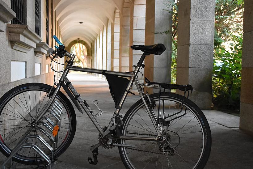 Bicicletas 2 mostrando una bicicleta urbana plateada aparcada en un soporte bajo un pórtico con arcos