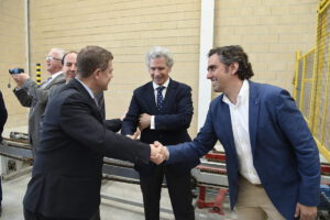 Hombres con traje estrechando manos frente a maquinaria en una planta industrial de biomasa 3