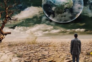 Persona mirando terreno agrietado y cielo oscuro que simboliza el cambio climatico