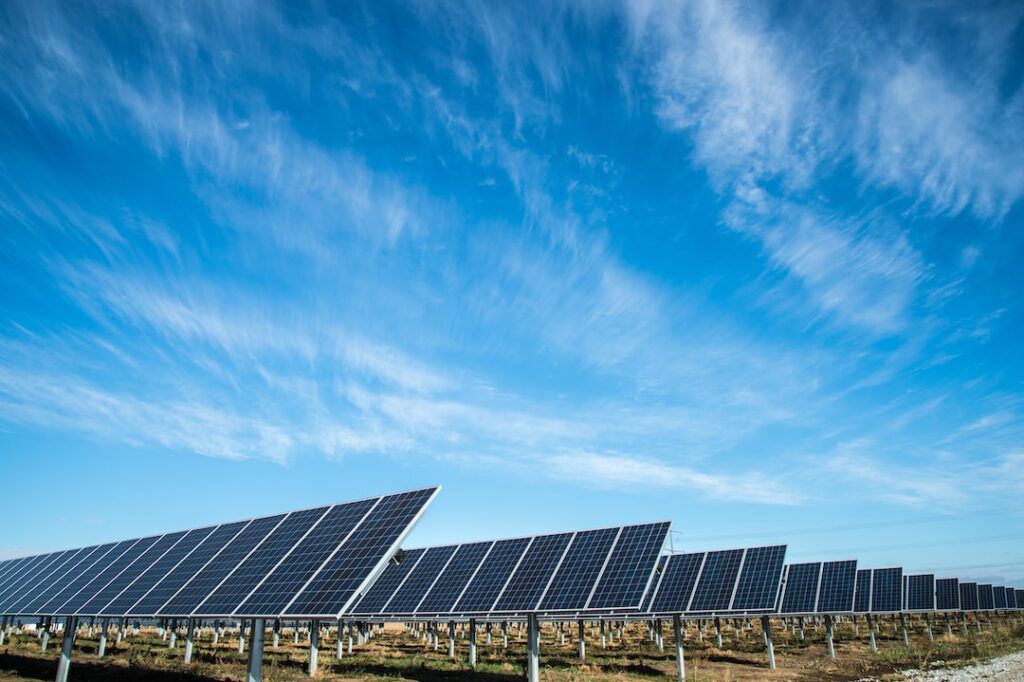 Filas de paneles solares en un campo bajo un cielo azul que ilustran como convertir energia solar electricidad guia practica.