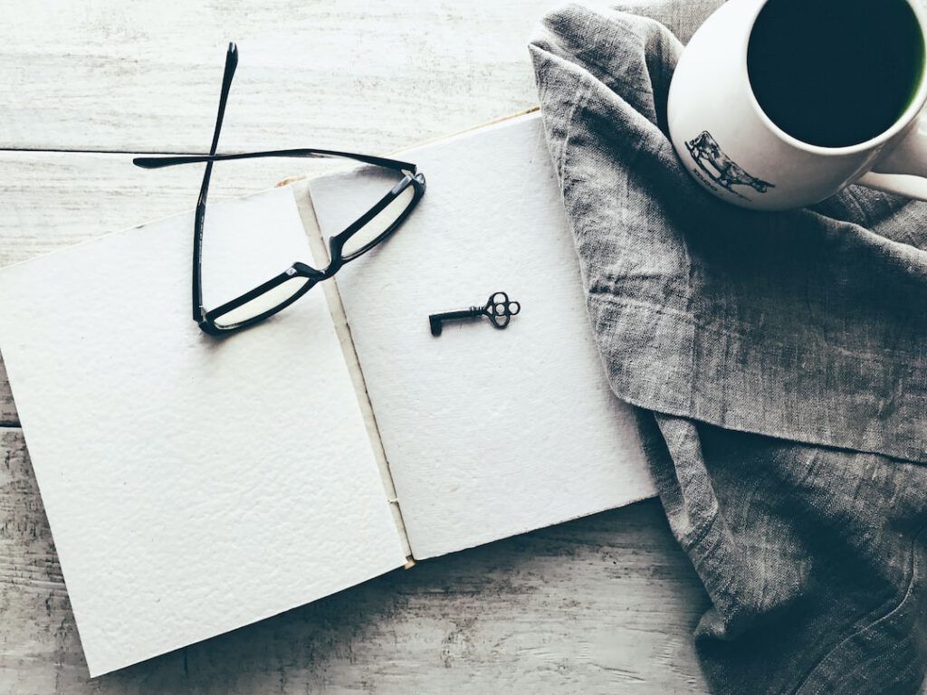 Cuaderno abierto con gafas, llave y taza que sugiere trabajo de campo sobre como determinar especie peligro extincion criterios