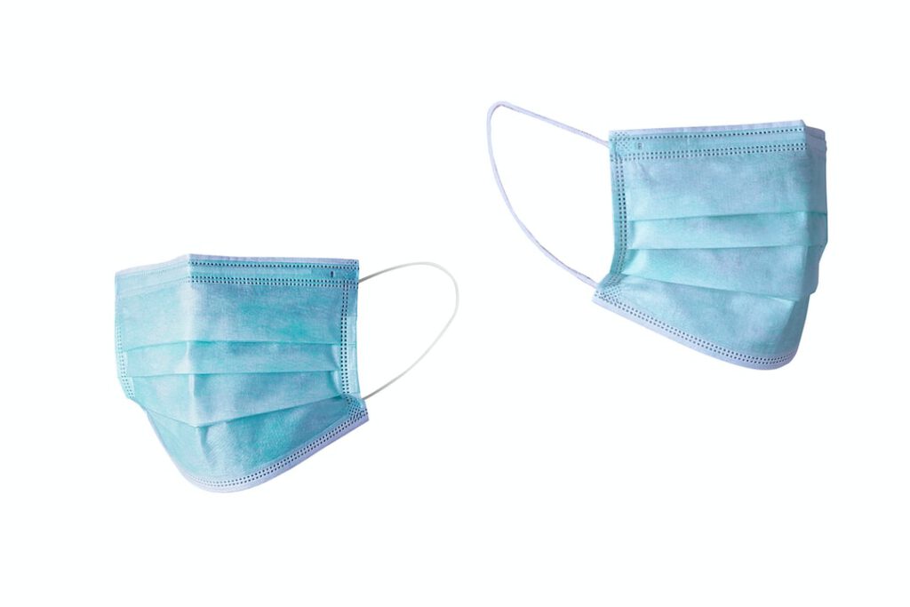 Dos mascarillas quirúrgicas azules sobre fondo blanco que ilustran como prevenir enfermedades contaminacion aire consejos efectivos.