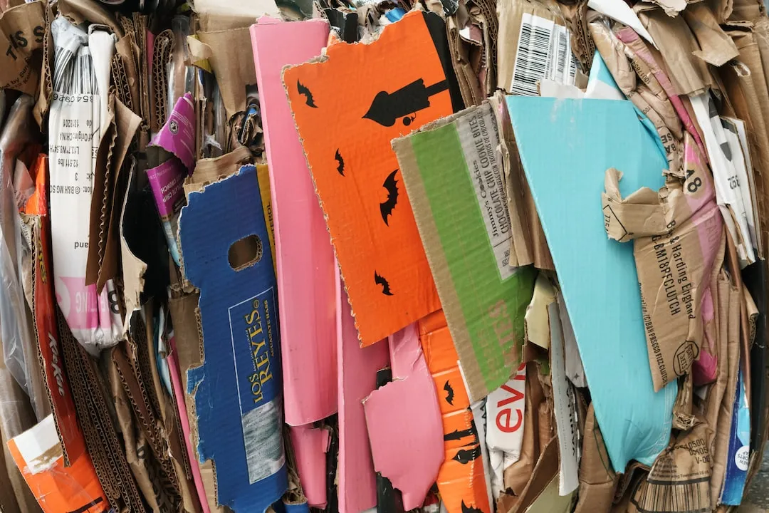 Una imagen de una mano sosteniendo papel usado y otro recipiente separado para el papel reciclable 