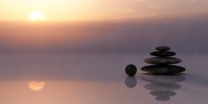 Piedras apiladas sobre agua reflectante al amanecer que evocan consejos reducir contaminacion acustica casa
