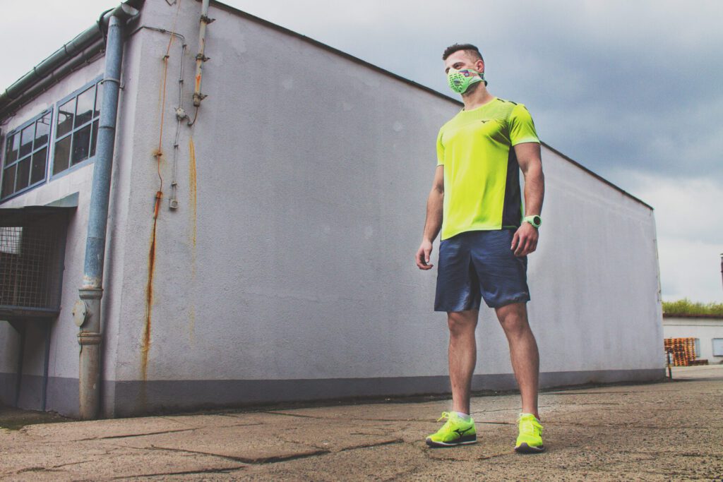 Hombre con ropa deportiva y mascarilla protegiéndose de la contaminacion del aire en un entorno urbano