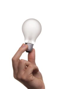 Mano sosteniendo una bombilla sobre fondo blanco, simbolizando creatividad 1