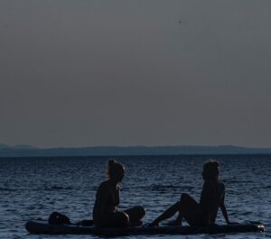 Dos personas en paddle sobre el mar al atardecer, descubre educar uso responsable agua ciudad