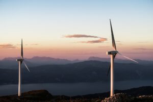 Turbinas eólicas al atardecer sobre montañas y lago que invita a descubre secreto almacenamiento energia aire comprimido