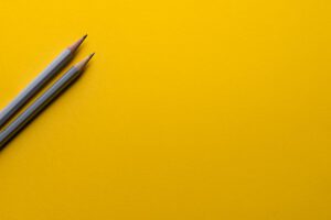 Dos lápices grises sobre fondo amarillo evoca análisis y reflexión sobre desventajas energia hidroelectrica impactos negativos