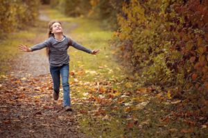 Niña corriendo por un sendero cubierto de hojas que evoca eco conciencia 1