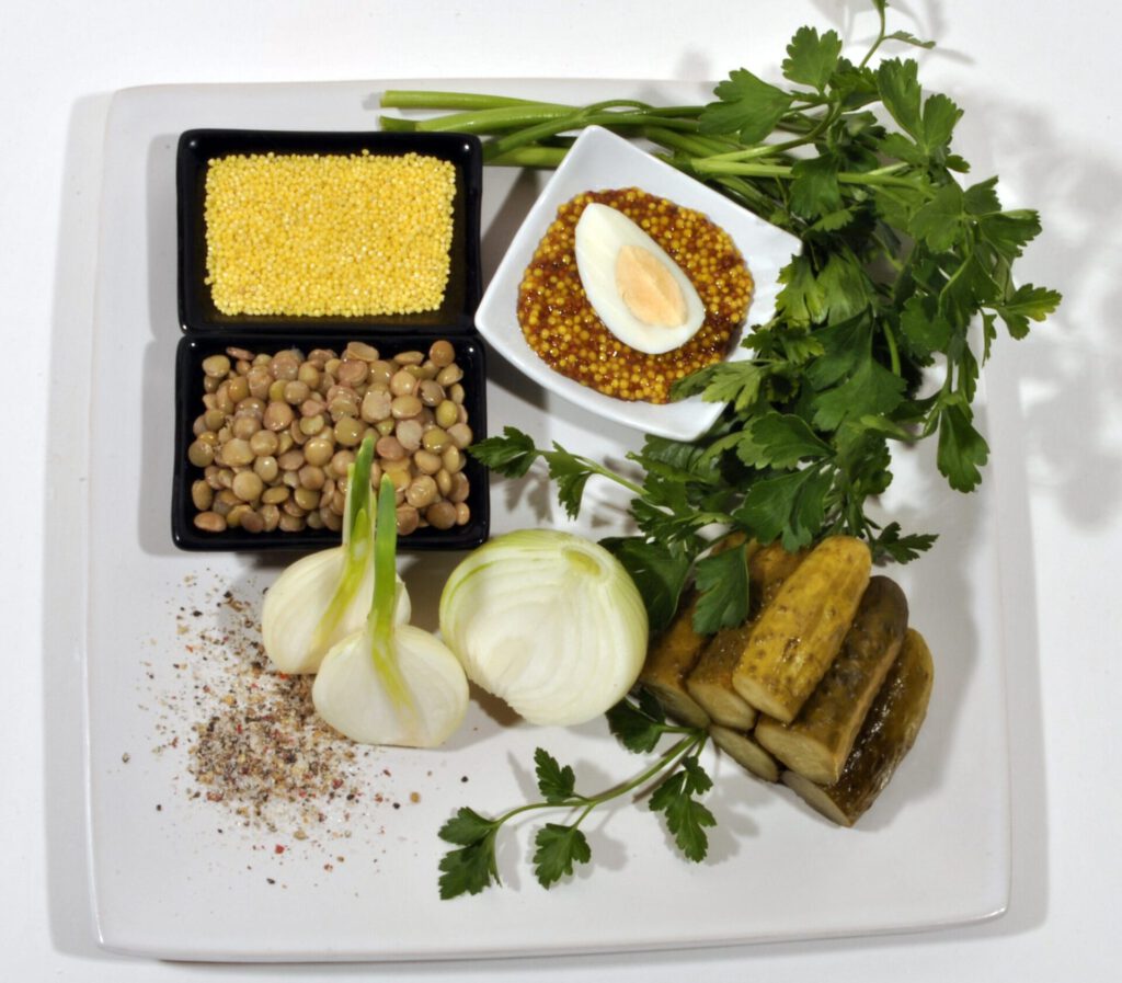 Plato con legumbres, mijo, mostaza en grano, huevo cocido, cebolla, pepinillos y perejil que sugiere eco friendliness