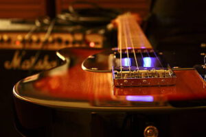 Primer plano de guitarra eléctrica mostrando pastillas y cuerdas que evocan el electromagnetismo.