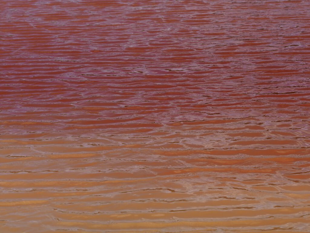 Superficie de agua rojiza y turbia que sugiere riesgo de enfermedades contaminacion agua.