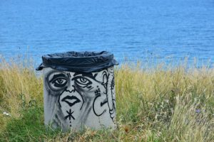 Bote de basura con grafiti en la costa junto al mar para ensena hijos uso responsable agua casa