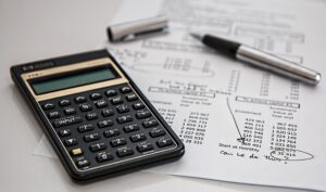 Calculadora, bolígrafo y hojas con cifras para planificar la financiacion infraestructuras seguras peatones ciclistas.