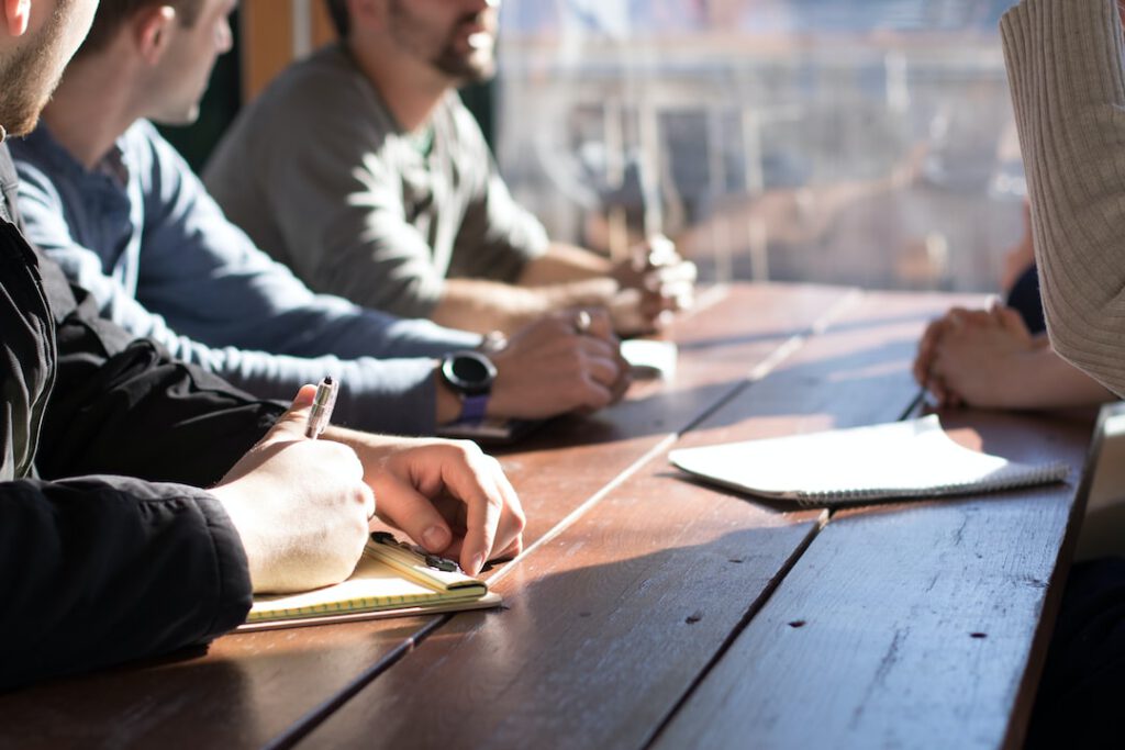 Personas en mesa tomando notas durante una reunión que fomenta colaboracion transporte movilidad eficiente