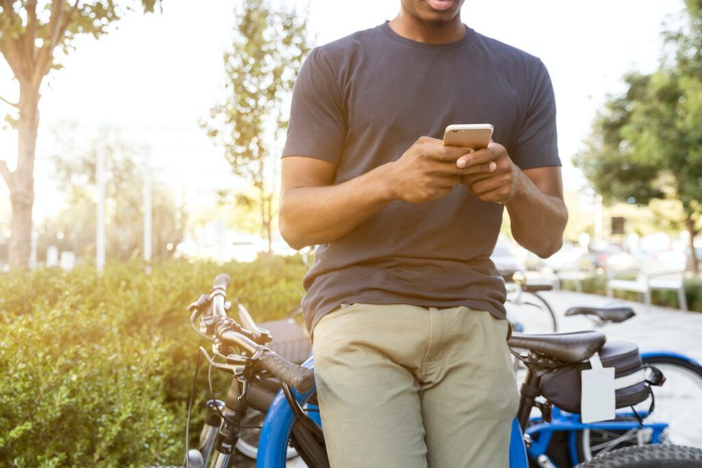 Persona apoyada en una bicicleta consultando el móvil, imagen que incentiva uso bicicletas trabajo consejos efectivos