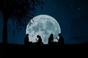 Siluetas de personas conversando bajo la luna llena en un encuentro comunitario, involucra comunidad drenaje sostenible aprende aqui