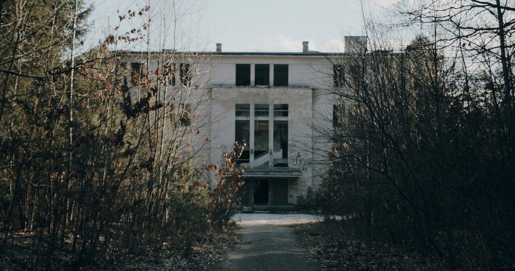 Edificio abandonado entre árboles desnudos que evoca los efectos cambio climatico planeta sociedad