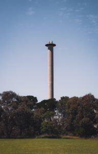 Torre tipo chimenea entre árboles y césped que ilustra medidas reducir contaminacion aire casa mediante control de fuentes y ventilación