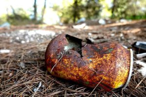 Lata oxidada y aplastada sobre suelo de pino con agujas secas naturaleza contaminada 1