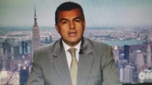 Presentador en estudio con traje y fondo de rascacielos que evoca naturaleza impactada 1