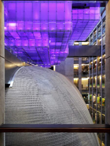Interior de atrio moderno con cúpula metálica texturizada y techo de paneles iluminados en púrpura, naturaleza restaurada 10