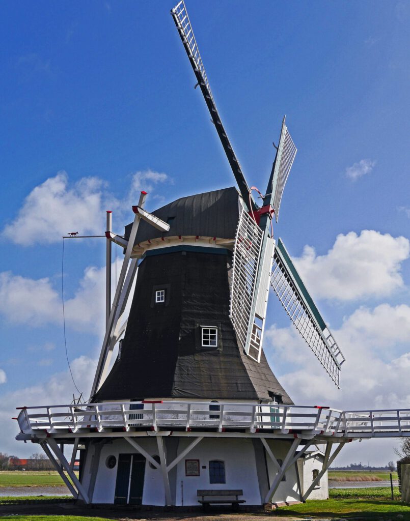 Molino tradicional con aspas blancas y pasarela rodeado de cielo azul en naturaleza restaurada 14.