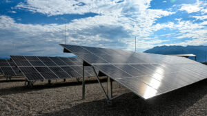 Paneles solares instalados en filas inclinadas sobre suelo de grava con reflejo del sol