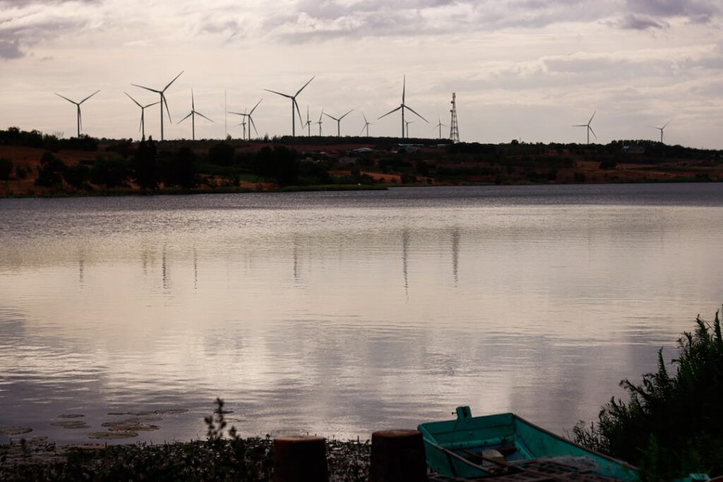 Embalse tranquilo con una barca en primer plano y molinos de viento en el horizonte, ilustración para principales productores energia hidroelectrica mundo