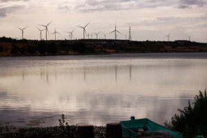 Embalse tranquilo con una barca en primer plano y molinos de viento en el horizonte, ilustración para principales productores energia hidroelectrica mundo