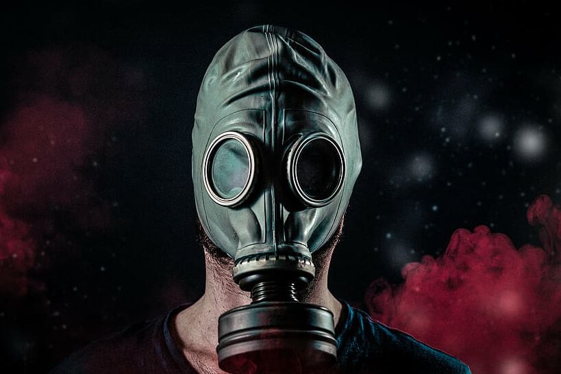 Persona con máscara antigás entre humo rojo oscuro evocando radiacion nuclear