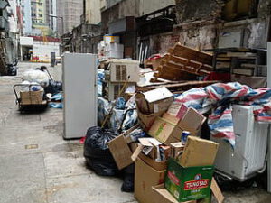 Montón de cajas, electrodomésticos y bolsas de basura en un callejón listo para reciclaje seguro