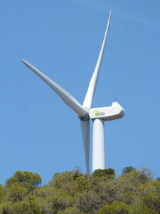 Aerogenerador blanco en colina bajo cielo azul que representa renovables y red electrica