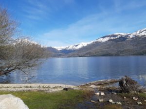 Lago sereno con montañas nevadas y orilla pedregosa que inspira responsabilidad compartida