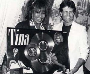 Dos personas sonrientes sosteniendo un disco conmemorativo enmarcado que ilustra una reutilizacion exitosa de material promocional.