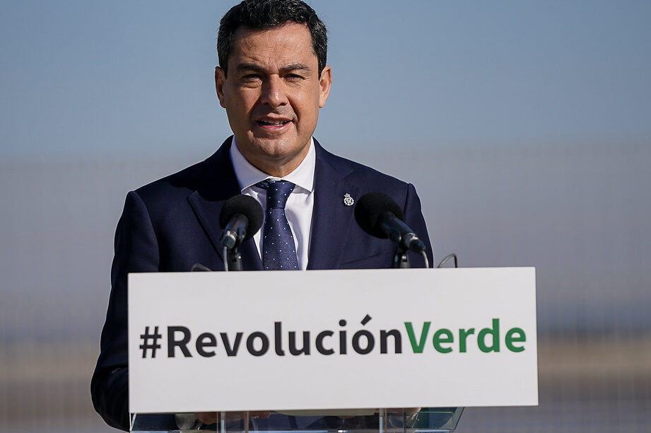 Hombre hablando en un podio con un cartel de Revolución Verde promoviendo riego eficiente 1