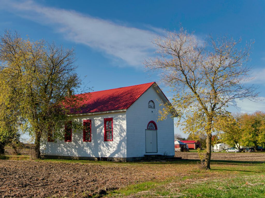 Edificio rural blanco con techo rojo entre campos y árboles otoñales para saber medir exito restauracion habitats degradados