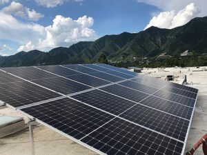 Paneles fotovoltaicos montados en un techo plano con montañas y cielo azul, solar 6.