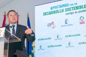 Orador con traje dando un discurso frente a una pantalla que promueve sostenibilidad 15 y desarrollo sostenible