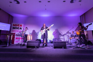 Banda tocando en un escenario iluminado en violeta durante evento sostenibilidad 6.
