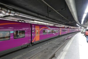 Tren morado detenido en una estación subterránea que ilustra transporte sostenible