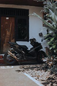 Moto negra aparcada frente a una casa con plantas y entrada rústica, evocando trucos lavar ropa ahorrar agua casa